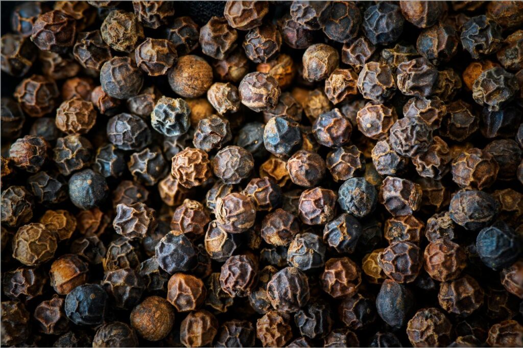 Rich texture and detail of whole black peppercorns in a macro shot.