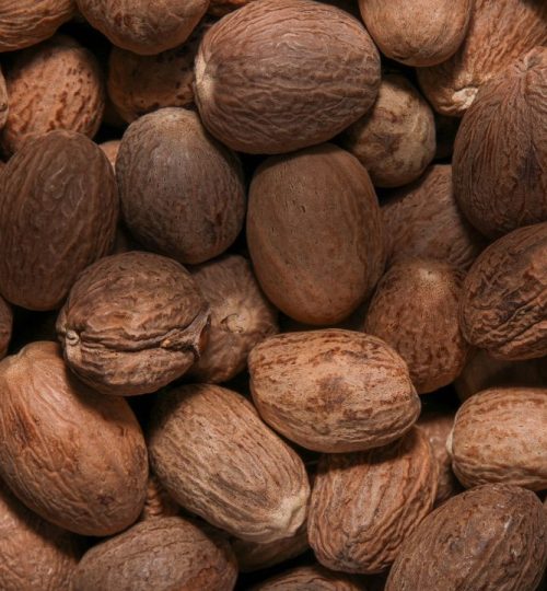 High-quality close-up image of whole nutmeg seeds with textured shells.